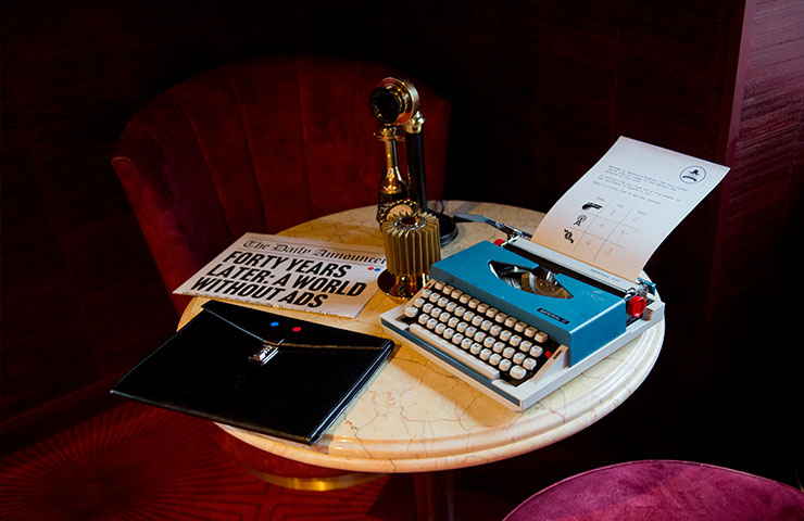 A selection of escape room props: a type writer, old phone, newspaper and lock folder