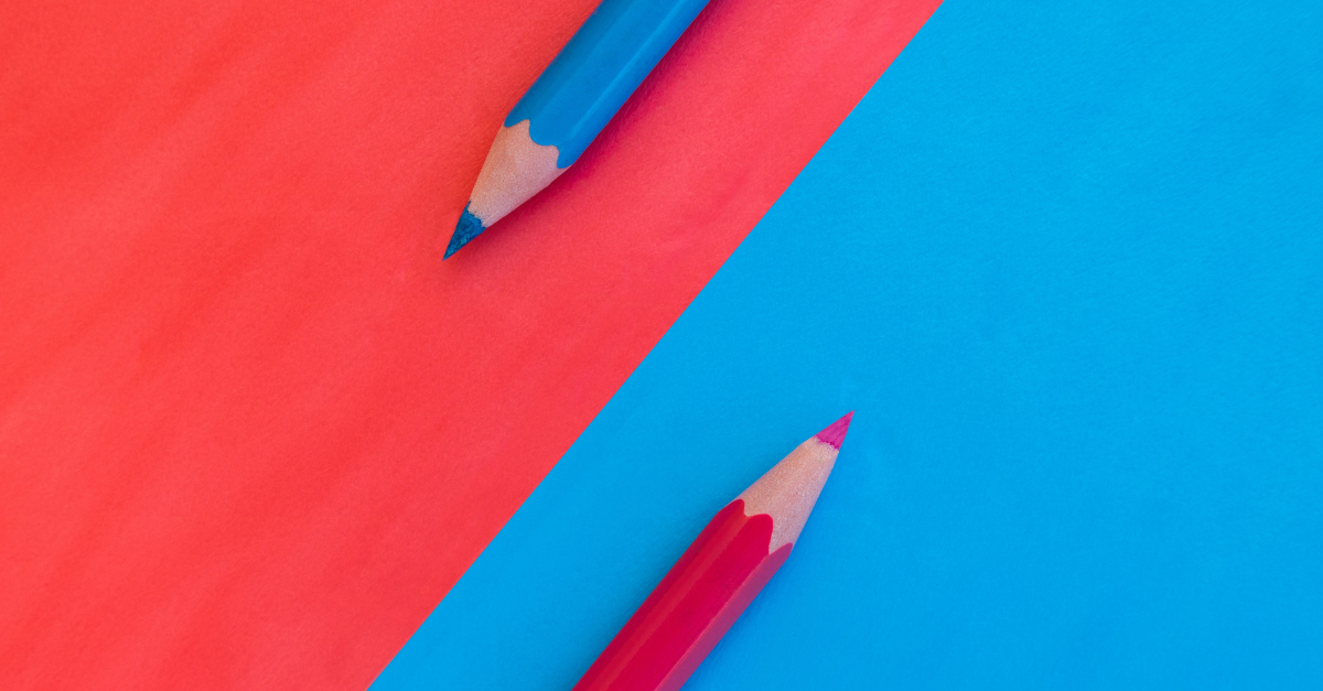 Two coloured pencils lie diagonally on contrasting red and blue backgrounds.